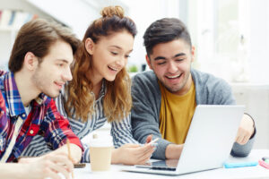 tres estudiantes mirando un ordenador portatil