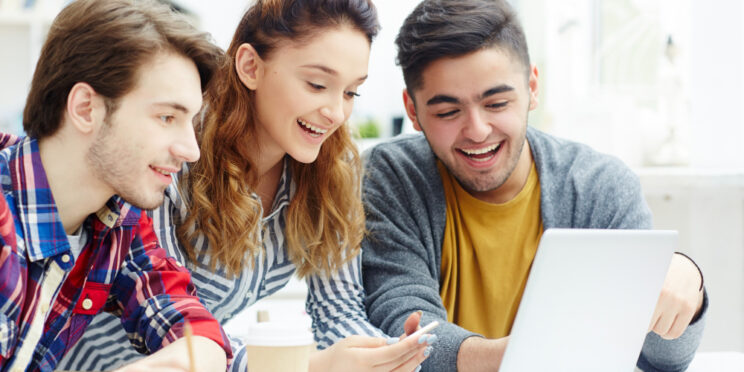 tres estudiantes mirando un ordenador portatil